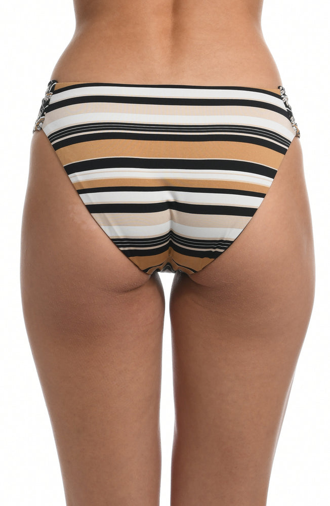 
            
                Load image into Gallery viewer, Model is wearing a retro inspired printed side shirred hipster swimsuit bottom with diagonal stripes and floral medallions in brown earthy tones from our 70&amp;#39;s Stripe collection.
            
        