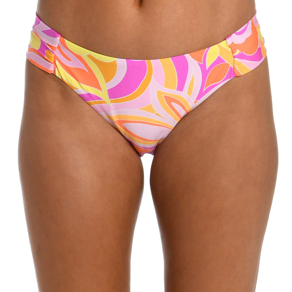 
                  
                    Model is wearing a pink, white, and orange multicolored retro printed side shirred hipster bikini bottom from our Retro Swirl collection.
                  
                