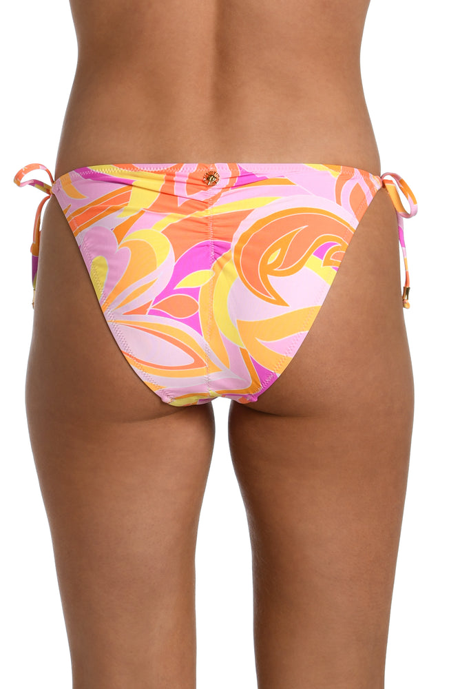 Model is wearing a pink, white, and orange multicolored retro printed side tie hipster bikini bottom from our Retro Swirl collection.