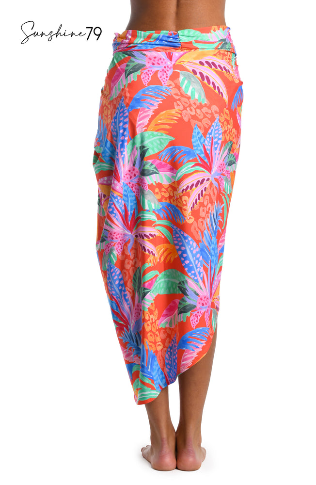 
            
                Load image into Gallery viewer, Model is wearing an orange multicolored tropical printed pull on faux pareo wrap cover up from our Sunshine 79 brand.
            
        