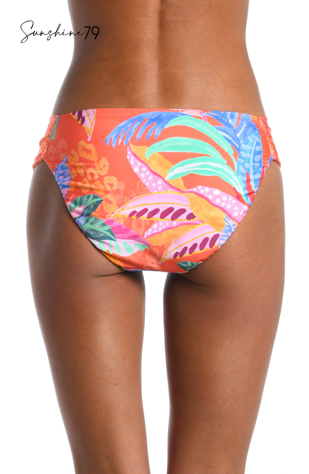 Model is wearing an orange multicolored tropical printed reversible side shirred hipster bikini bottom from our Sunshine 79 brand.