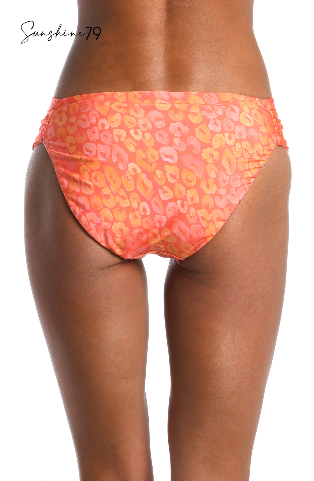 Model is wearing an orange multicolored tropical printed reversible side shirred hipster bikini bottom from our Sunshine 79 brand.