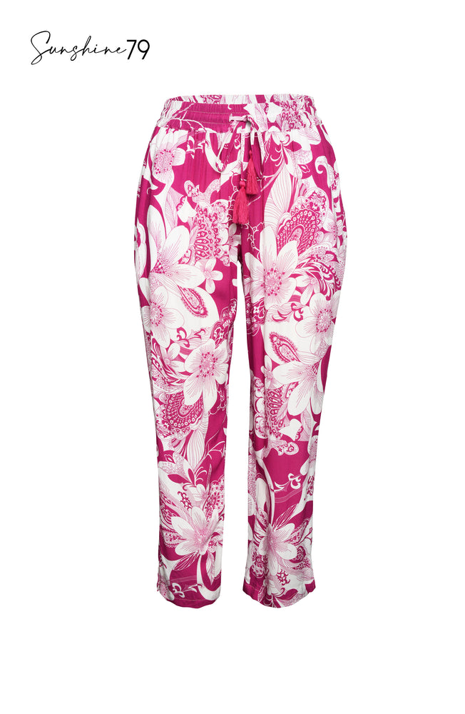 Model is wearing a fuchsia and white multicolored tropical printed beach pant cover up from our Sunshine 79 brand.