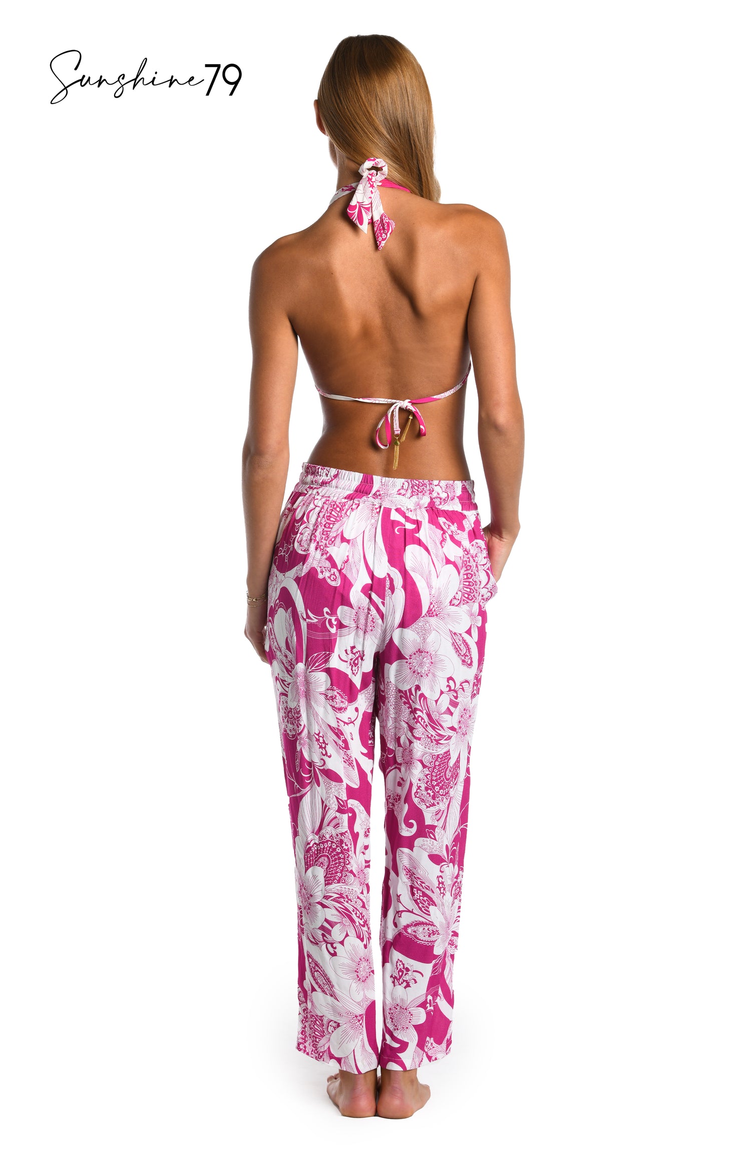 Model is wearing a fuchsia and white multicolored tropical printed beach pant cover up from our Sunshine 79 brand.