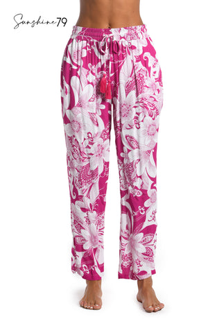 Model is wearing a fuchsia and white multicolored tropical printed beach pant cover up from our Sunshine 79 brand.