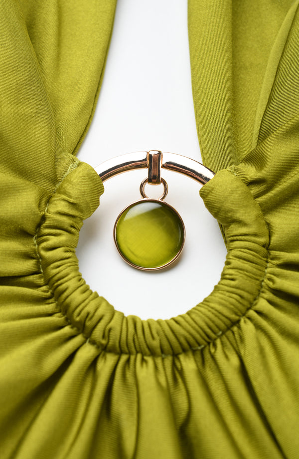 Olive green fabric with a gold ring and pendant on a white background