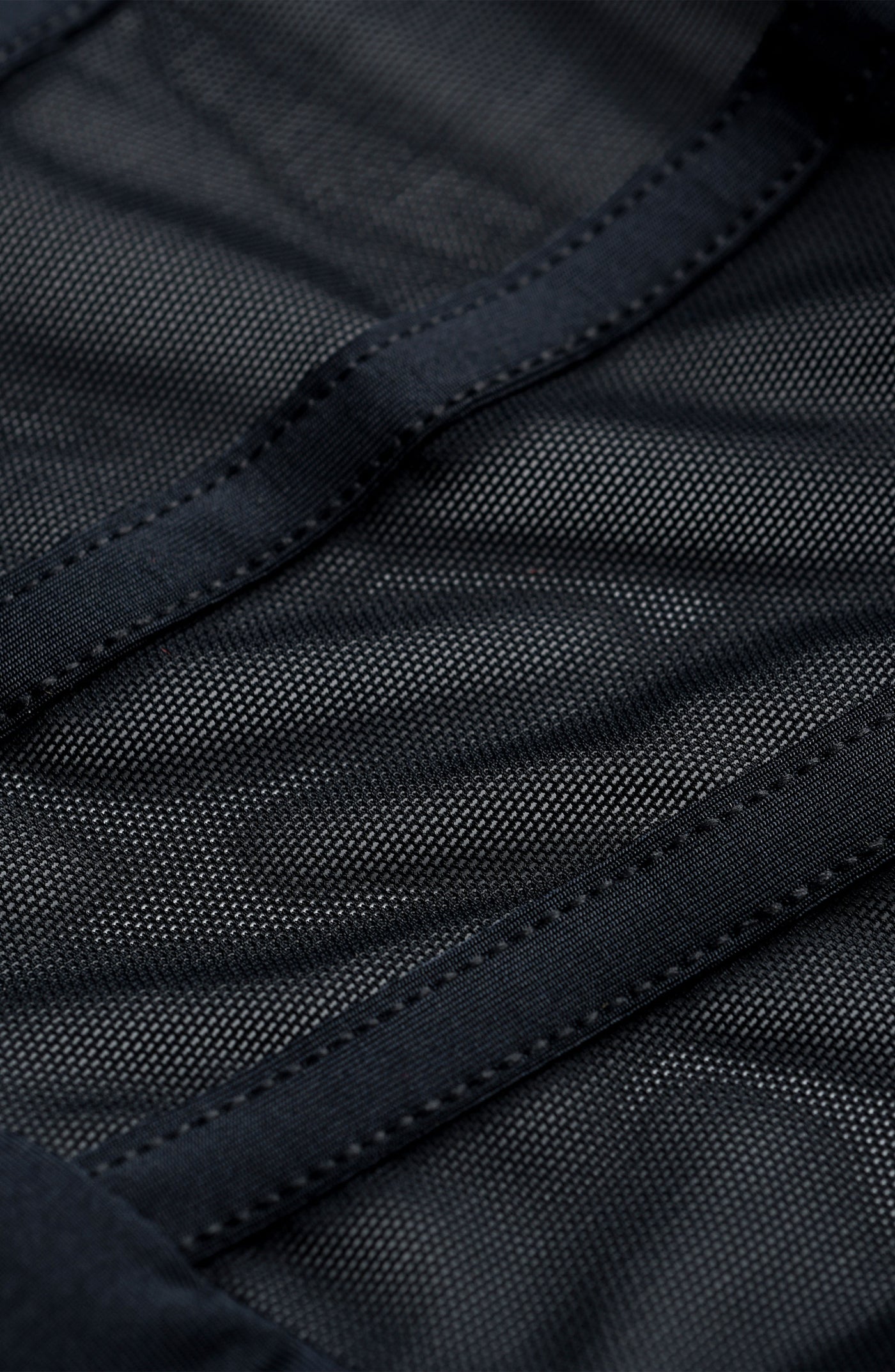 
                  
                    Close-up of black sheer fabric with stitching detail
                  
                