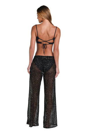 Model is wearing a black colored sheer beach pant cover up.