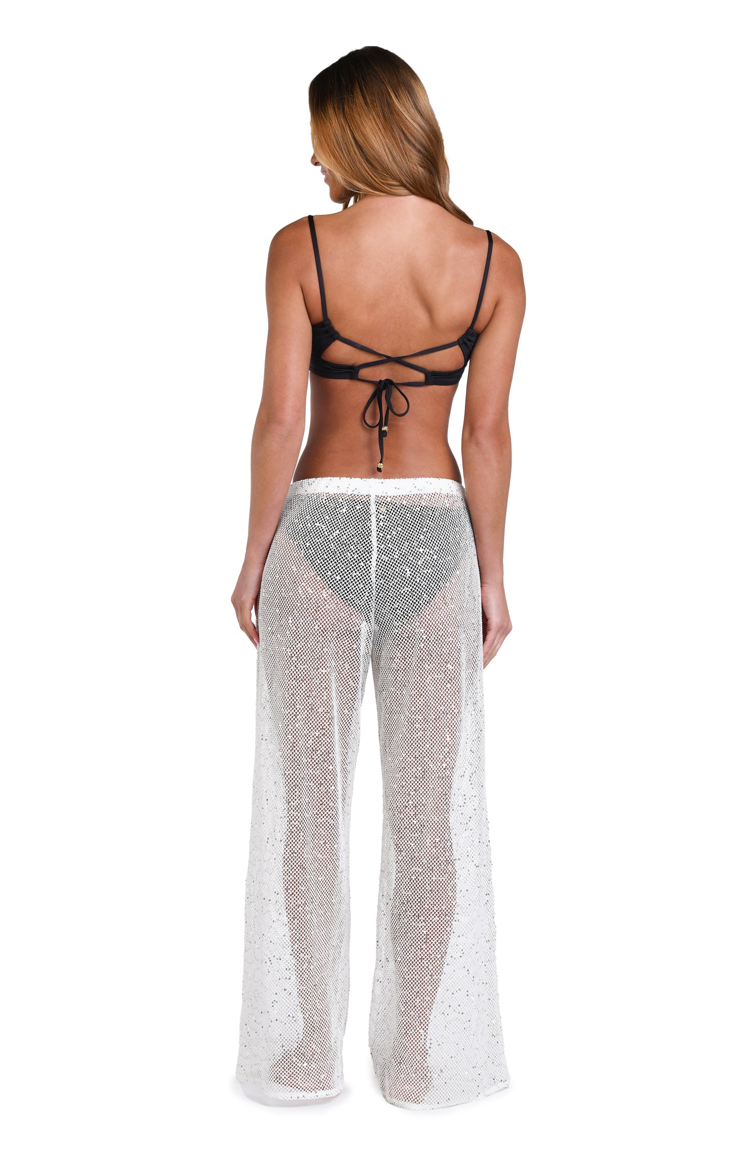 Model is wearing a white colored sheer beach pant cover up.
