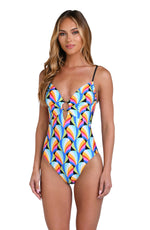 Model is wearing a pink, blue, yellow, and orange multicolored over the shoulder triangle bikini top on a geometric patterned black background.