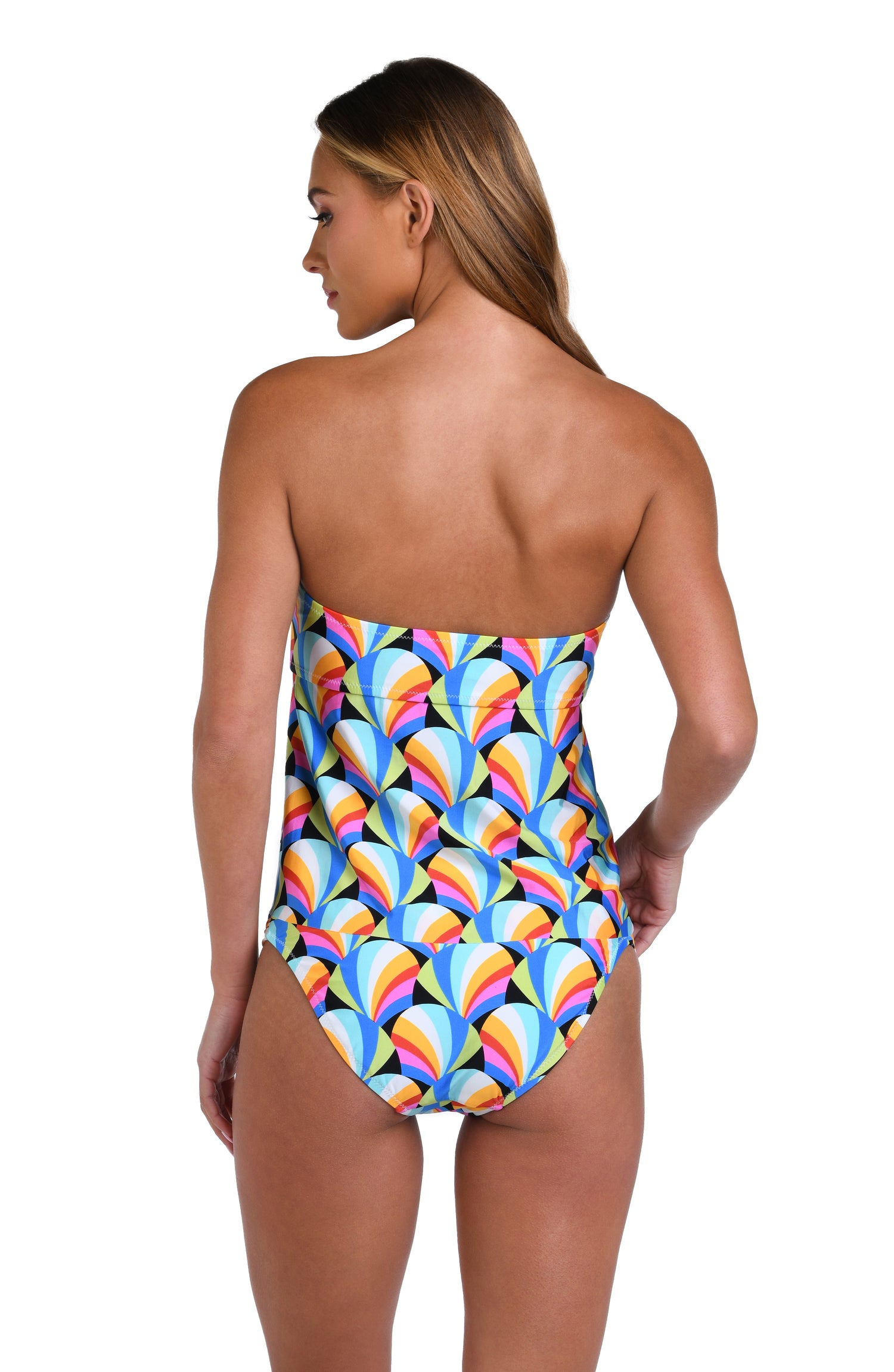 Model is wearing a pink, blue, yellow, and orange multicolored bandeau tankini top on a geometric patterned black background.
