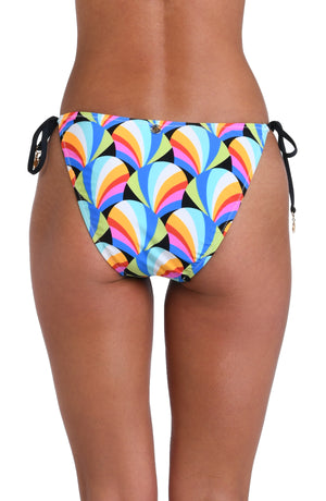 Model is wearing a pink, blue, yellow, and orange multicolored side tie hipster bikini bottom on a geometric patterned black background.