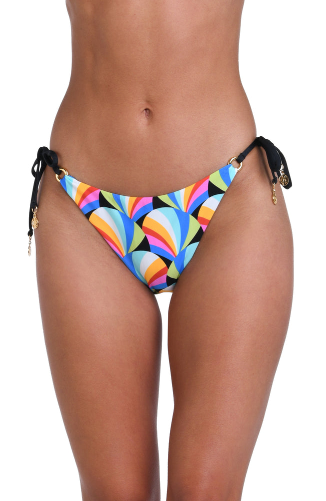 Model is wearing a pink, blue, yellow, and orange multicolored side tie hipster bikini bottom on a geometric patterned black background.