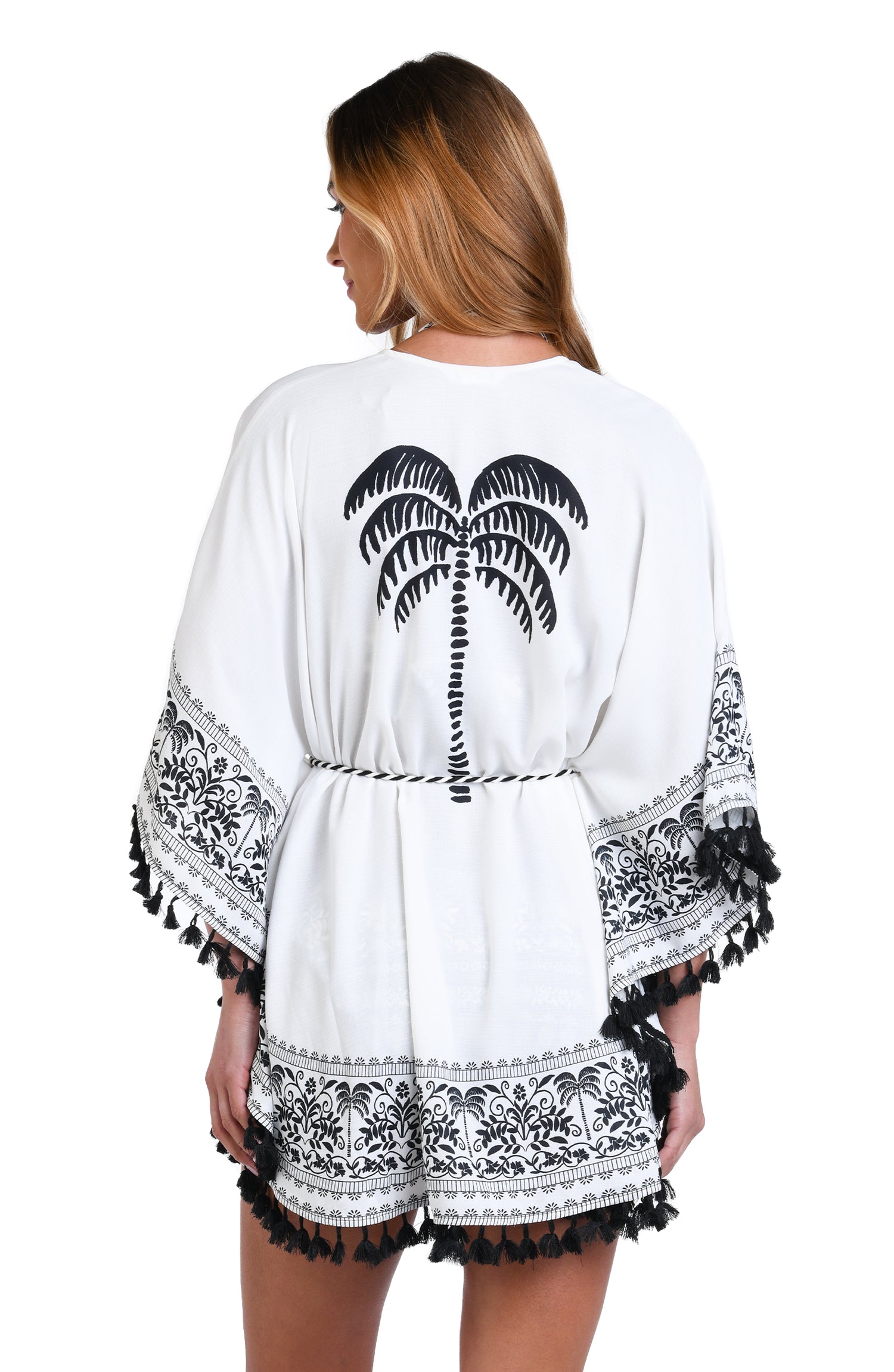 Model is wearing a black and white monochromatic patterned kimono cover up that features an allover tropical motif with hints of palm trees and pineapples set against a black background.