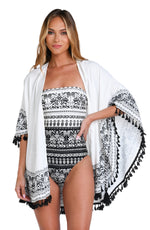 Model is wearing a black and white monochromatic patterned kimono cover up that features an allover tropical motif with hints of palm trees and pineapples set against a black background.