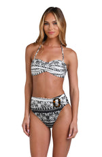 Model is wearing a black and white monochromatic patterned bandeau bikini top that features an allover tropical motif with hints of palm trees and pineapples set against a black background.