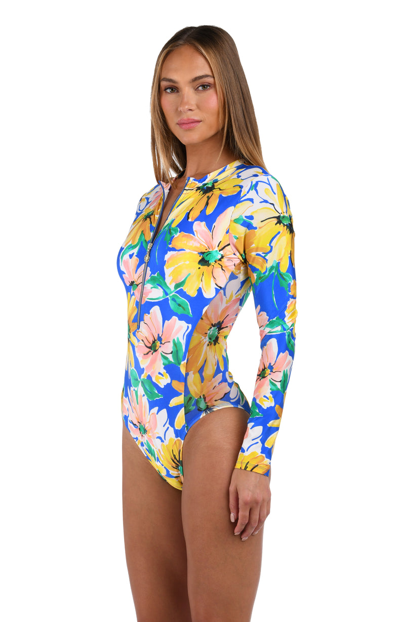 Side image of model wearing the Sunflower Getaway Paddlesuit One Piece in a multi colored tropical print.