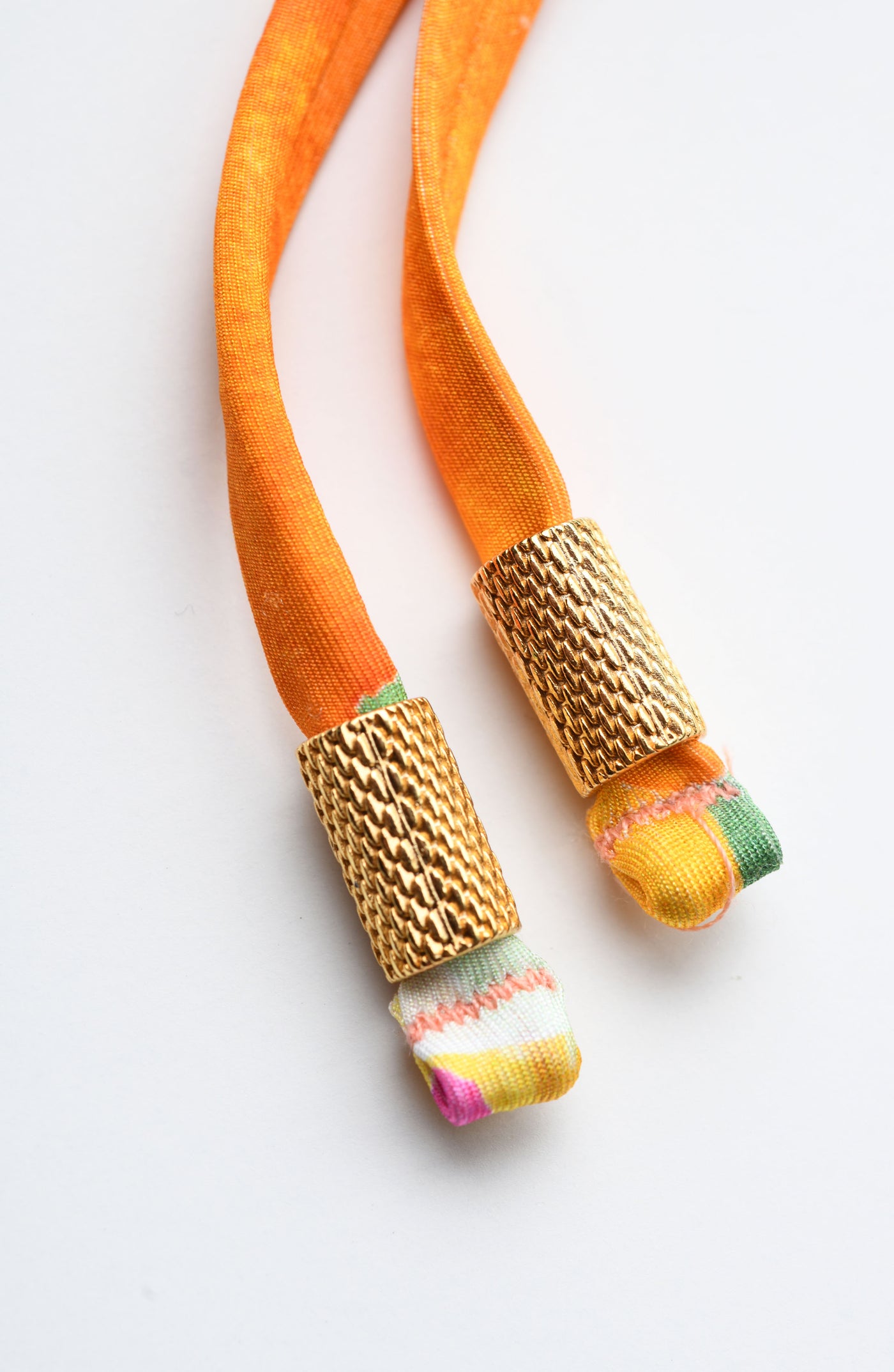 
                  
                    Close-up of multicolored tassels with gold tip ends. 
                  
                
