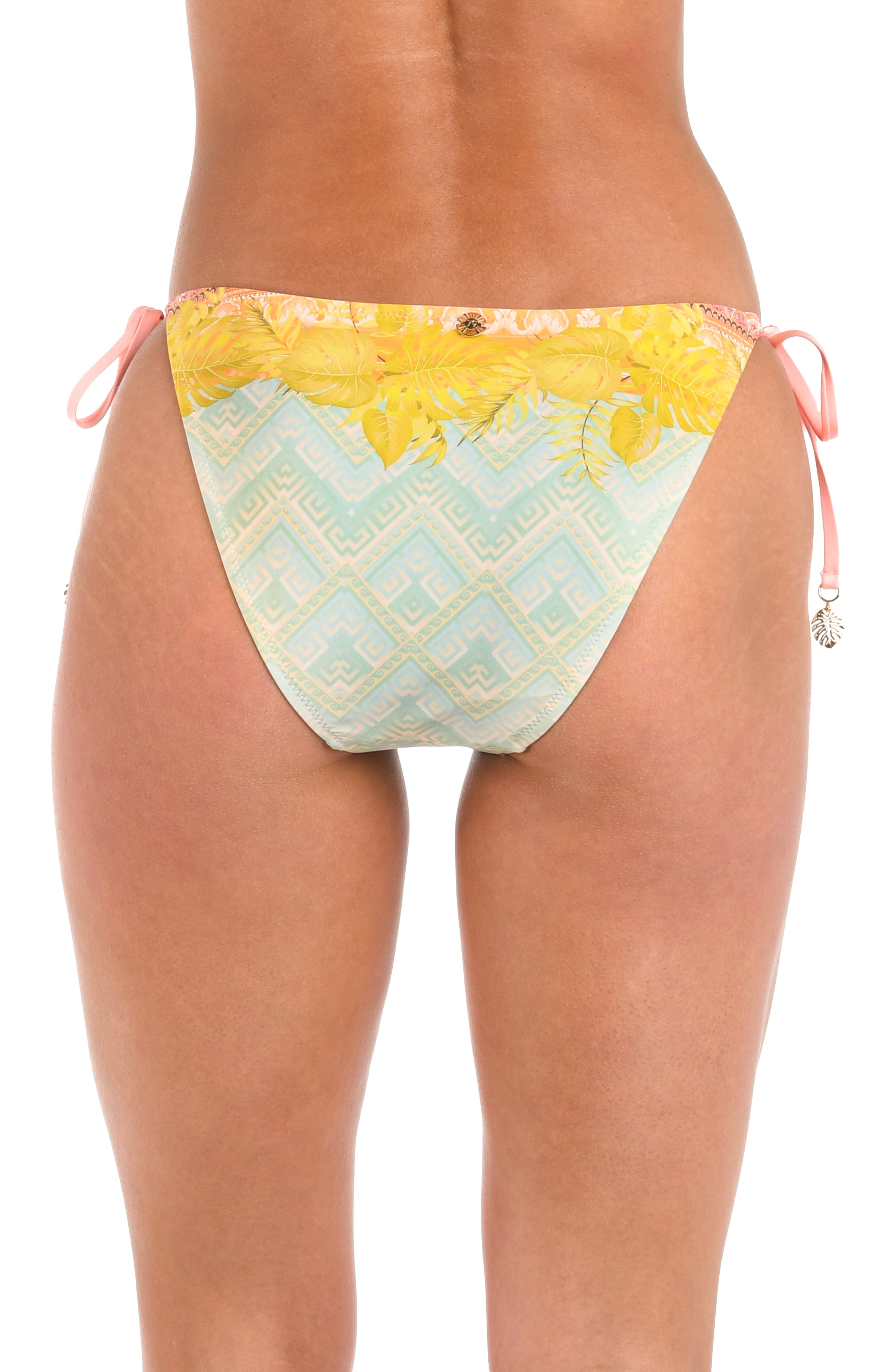Back image of model wearing a multi-colored pastel yellow, green, and peach patterned hipster bikini swimsuit bottom featuring side ties, tassels, and moderate rear coverage.