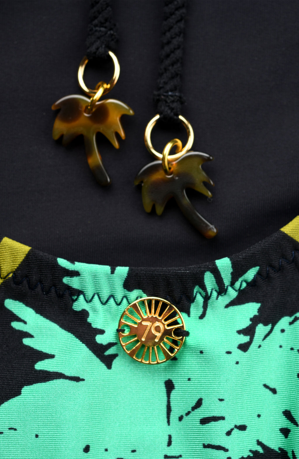 Gold palm tree charms on a black and green fabric background