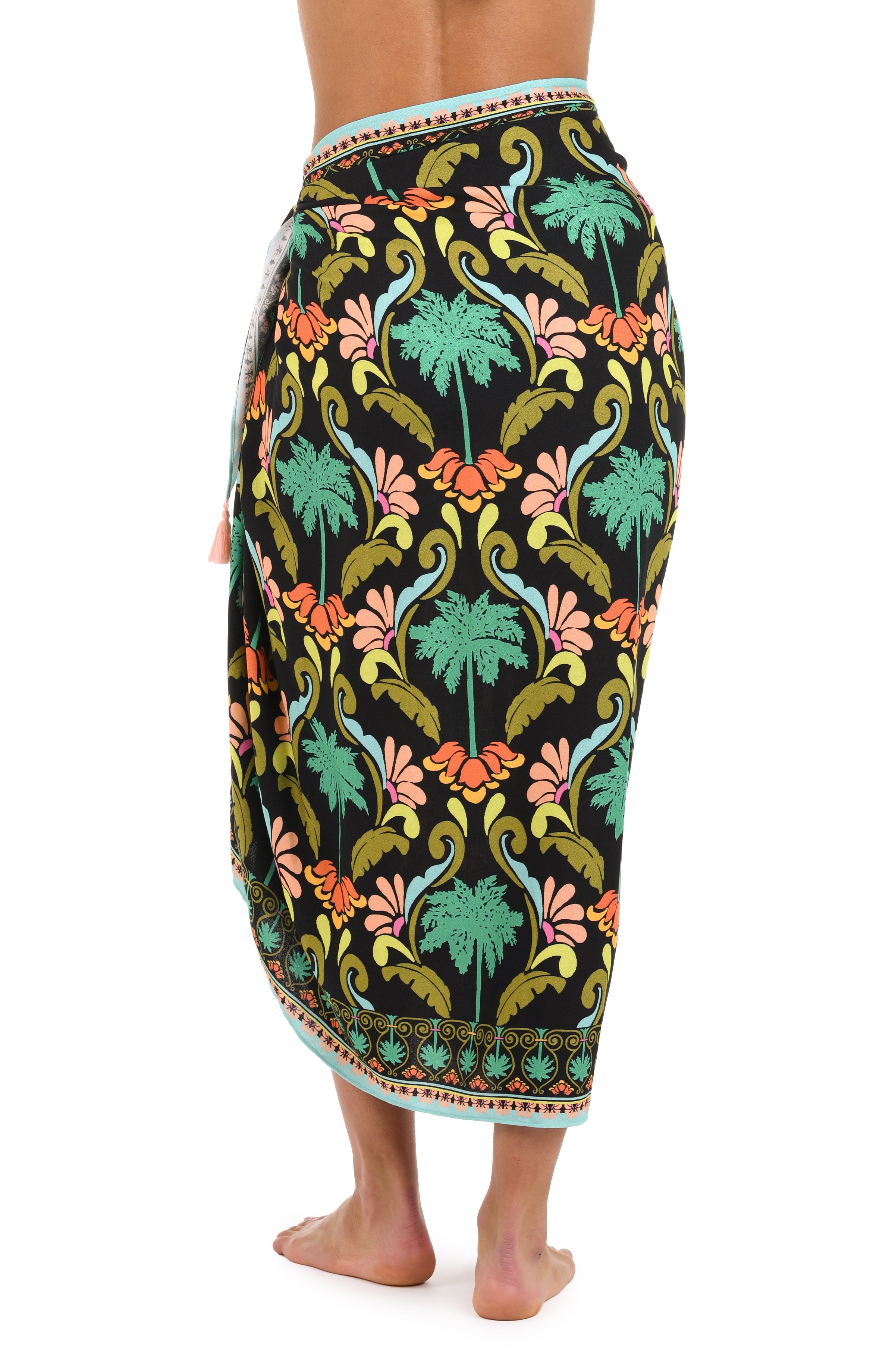 Back image of model wearing a multi-colored pareo wrap cover up with a tropical-inspired design. 