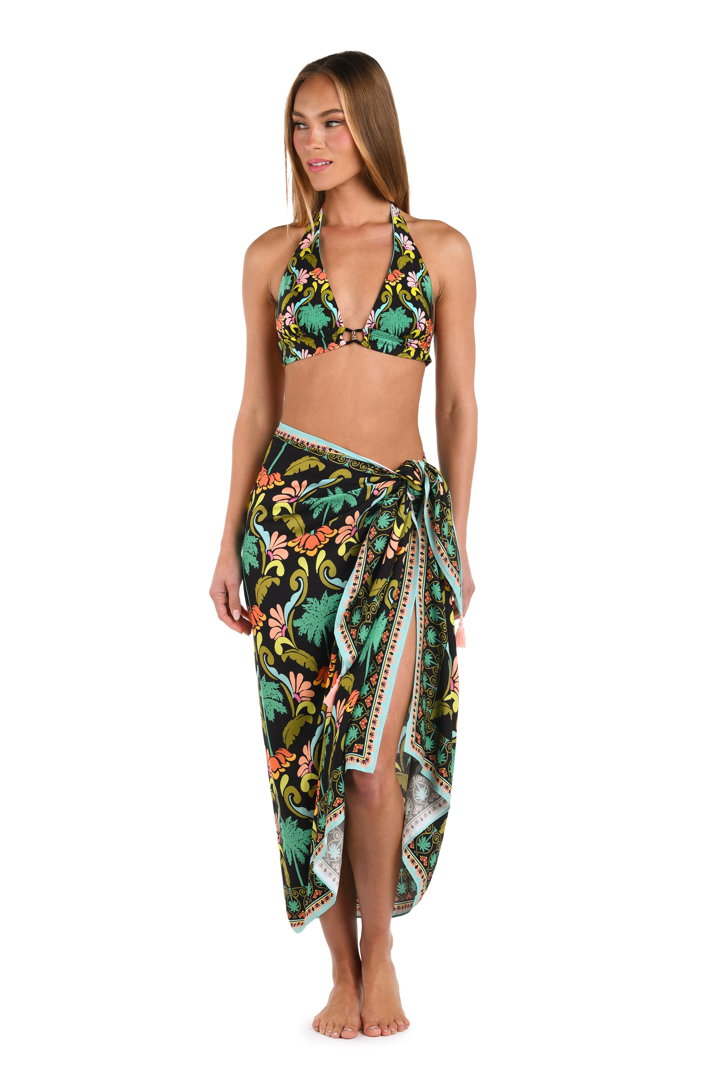 Full body front image of model wearing a multi-colored pareo wrap cover up with a tropical-inspired design. 