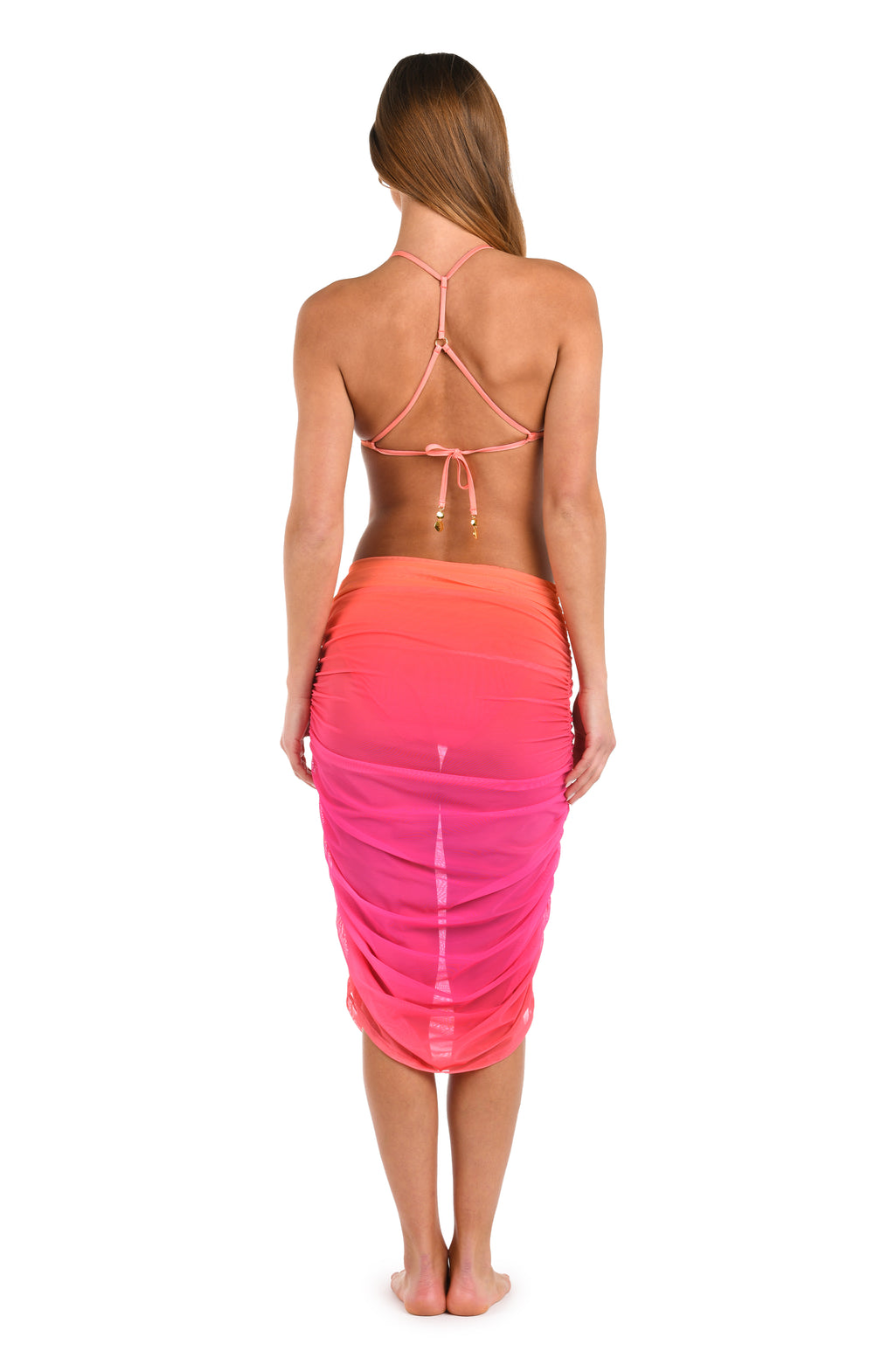 Full body back image of model wearing a pull-on mesh skirt cover up, featuring an Ombre design in vibrant orange and pink. 