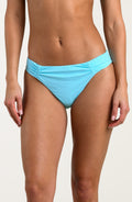 Person wearing a turquoise bikini bottom against a white background