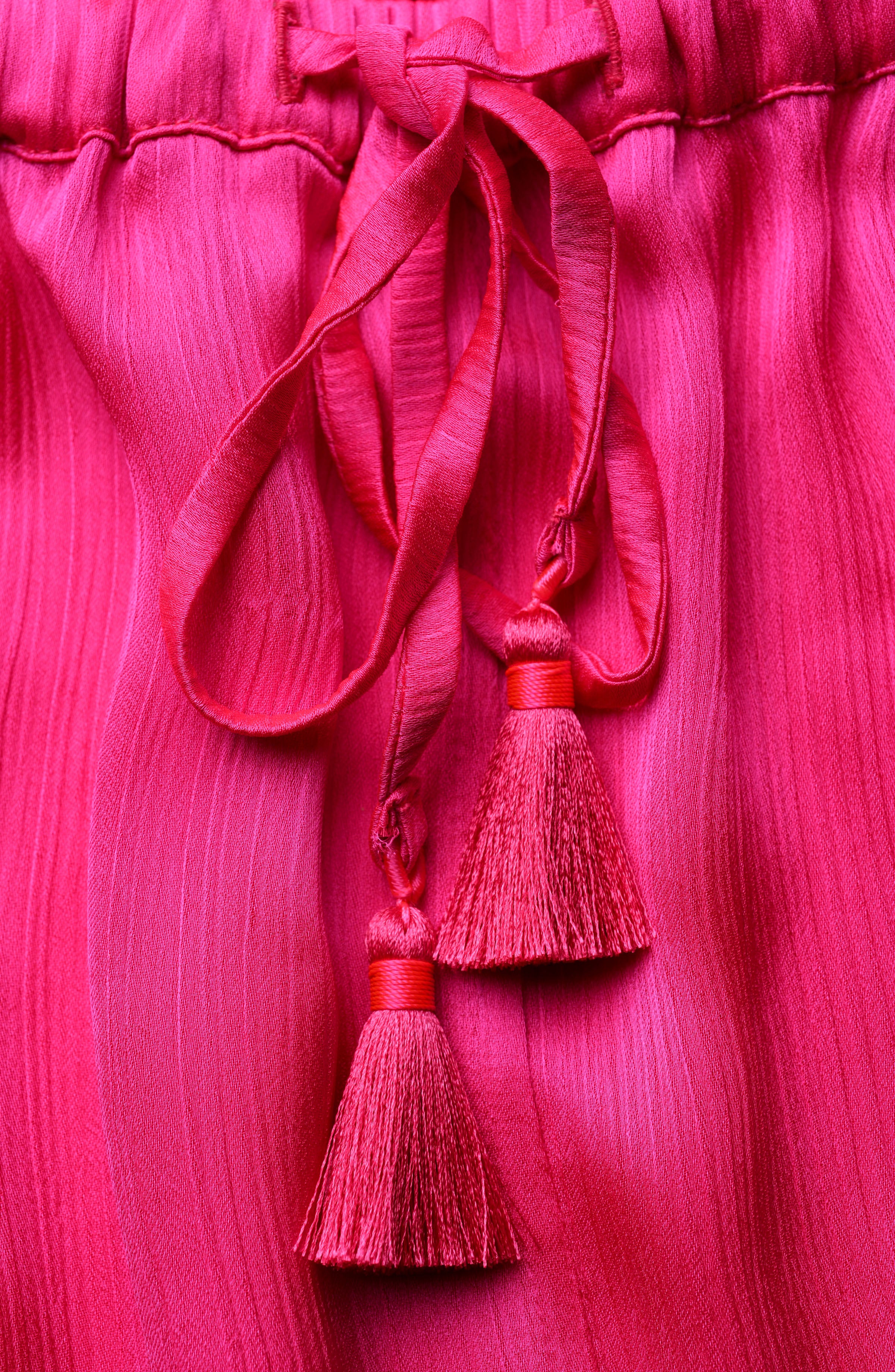 Close-up of a pink fabric with tassels on a matching pink background