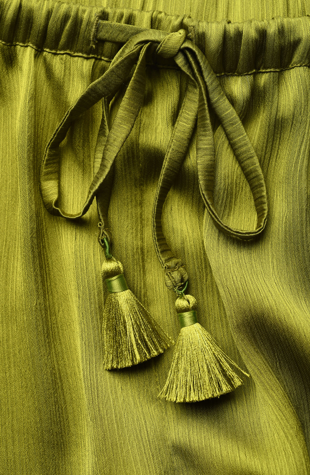 Close-up of olive green fabric with tassels on a matching green background