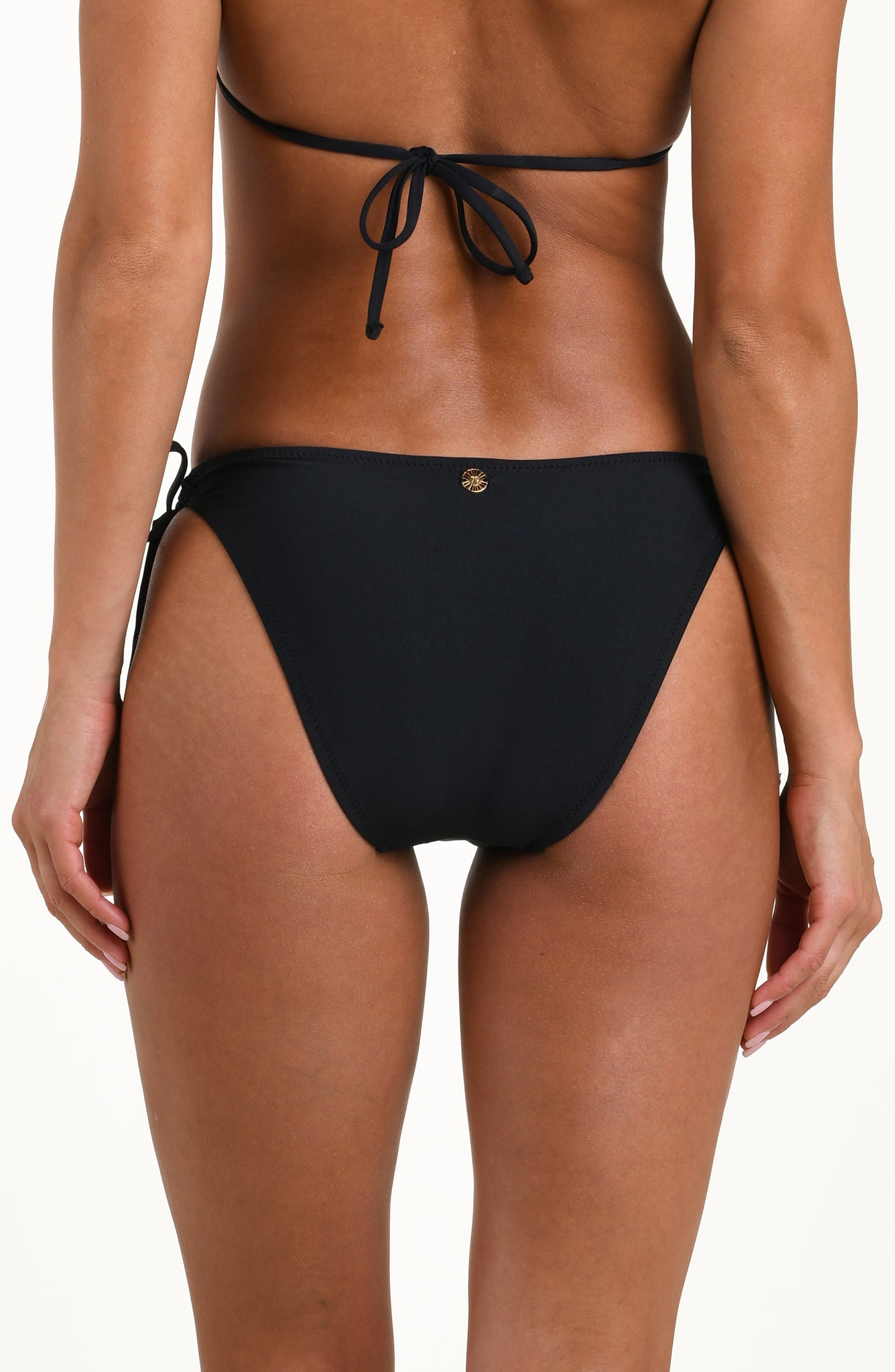 
                  
                    Back image of model wearing solid black bikini bottoms with adjustable side  ties featuring gold dipped ends, a gold charm at center, and contemporary rear coverage.
                  
                