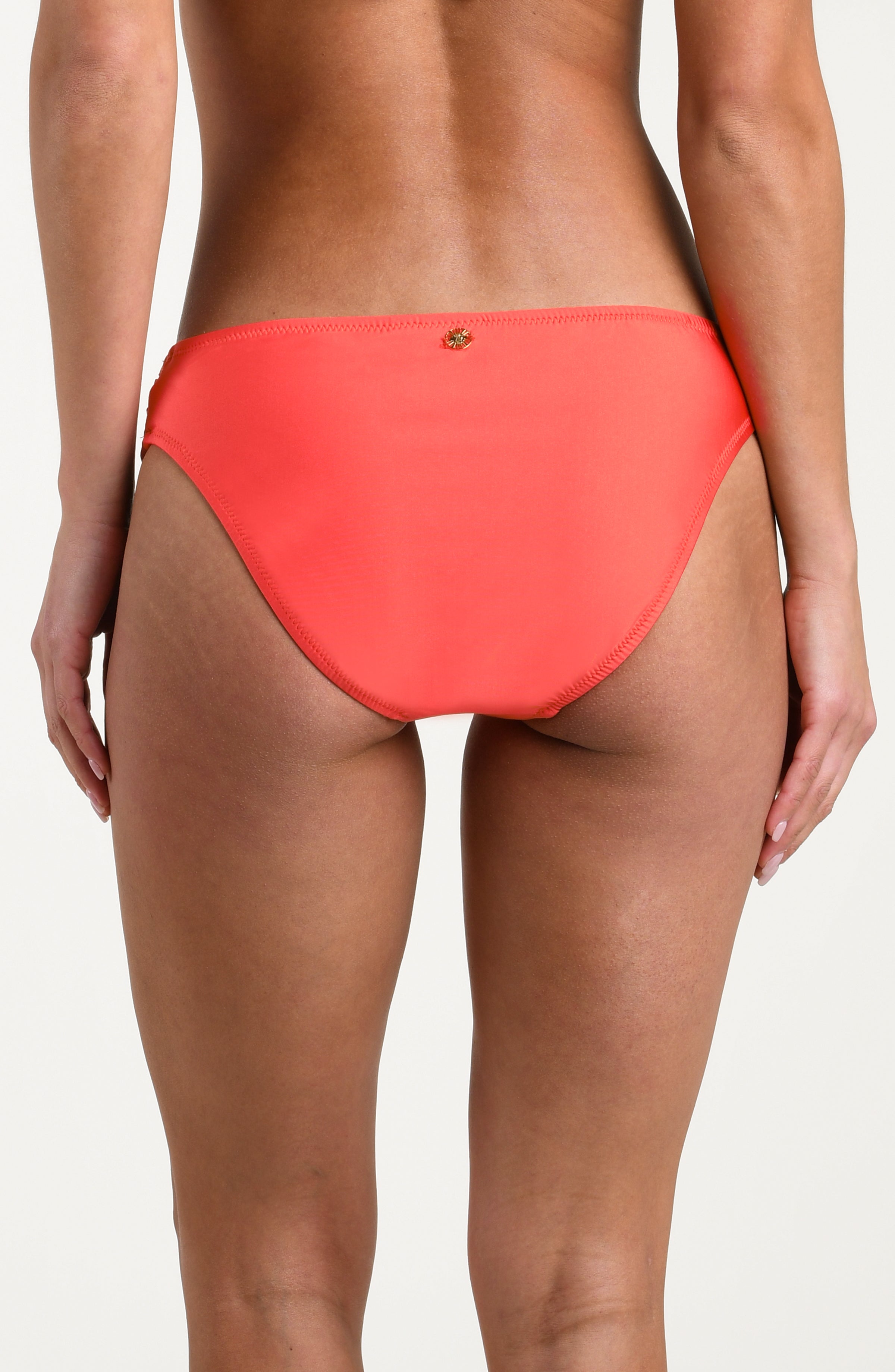 Bright orange bikini bottom with a gold ring detail on a white background