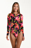 Front image of model wearing a long sleeve paddle suit one piece featuring a zipper front, in a multicolored floral print.