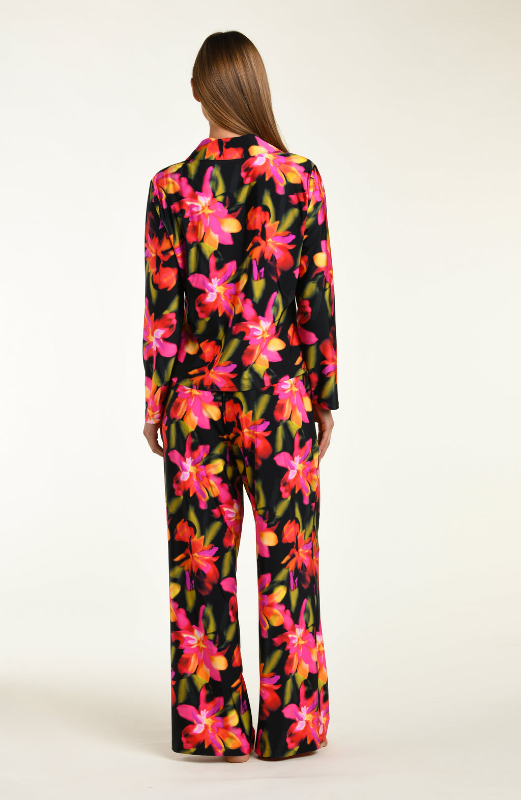 Woman wearing a colorful floral shirt and pant pajama set on a white background