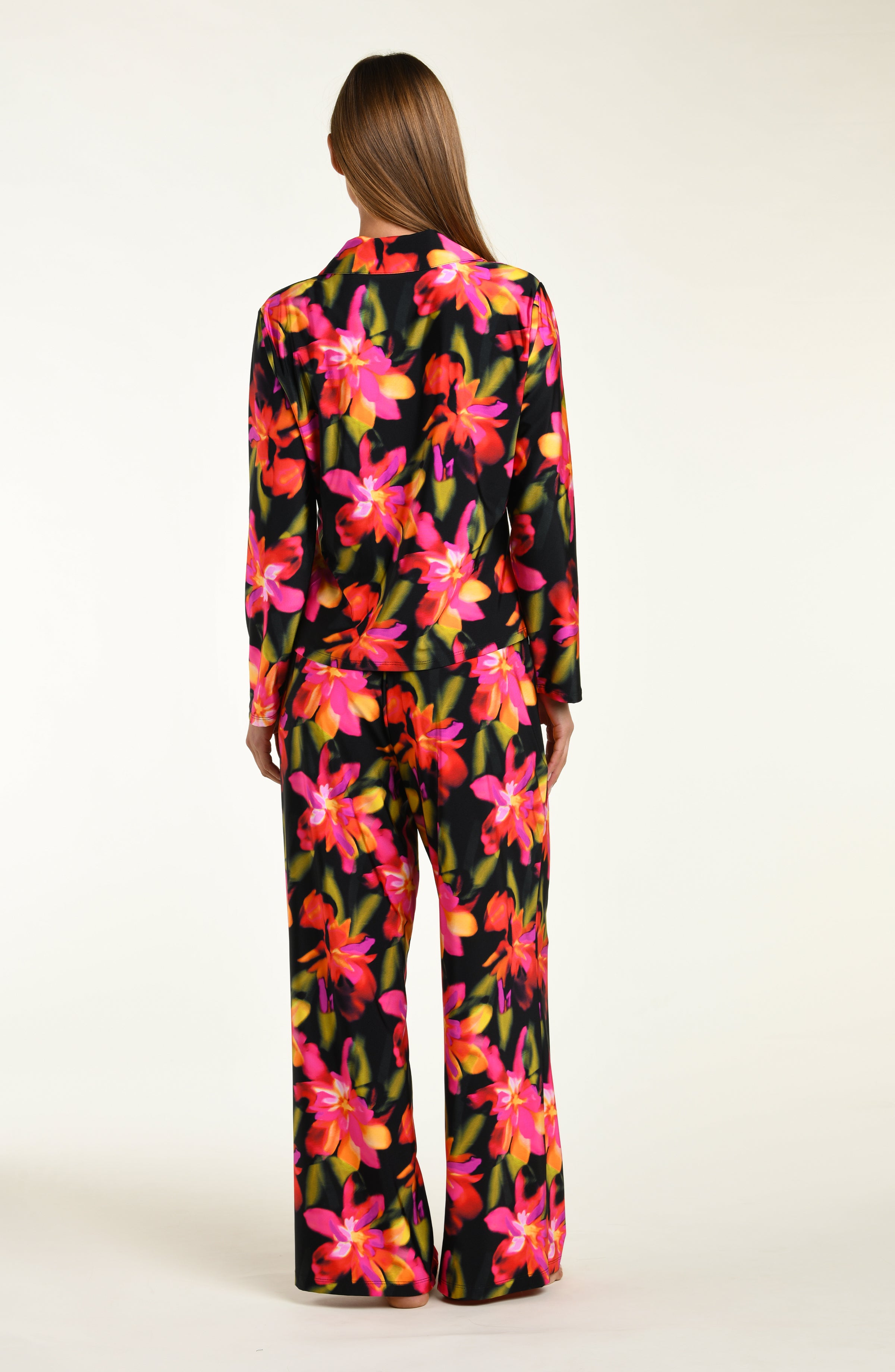 Woman wearing a colorful floral shirt and pant pajama set on a white background