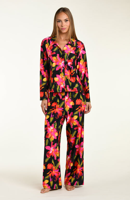 Woman wearing a colorful floral shirt and pant pajama set on a white background