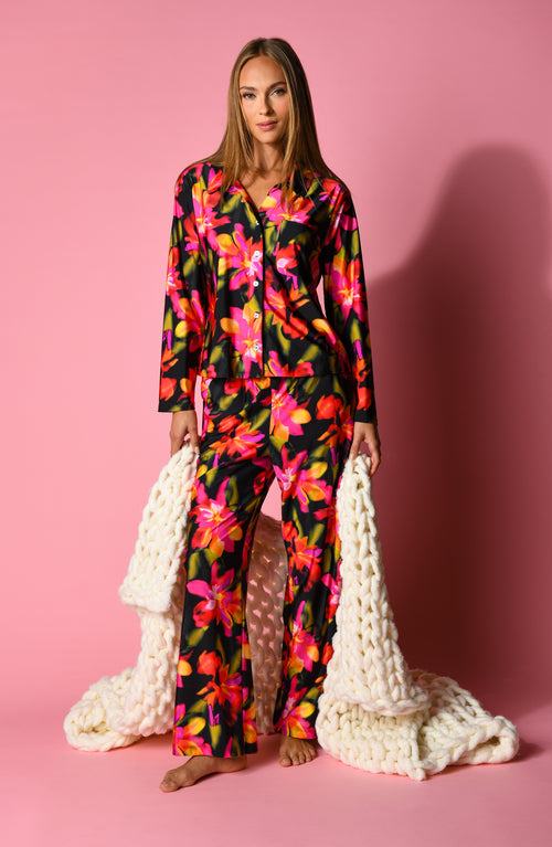 Woman wearing a colorful floral pajama set on a pink background