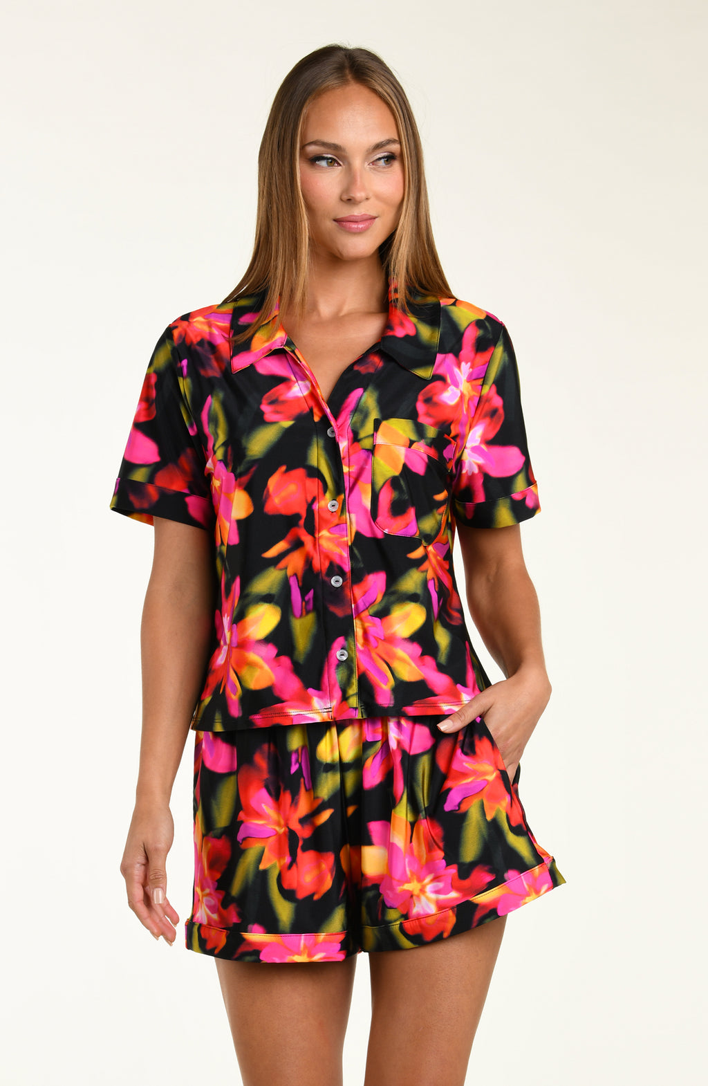 Woman wearing a colorful floral shirt and short pajama set on a white background