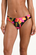 Front image of model wearing bikini bottoms with side ruching and moderate coverage in a multicolored floral print.