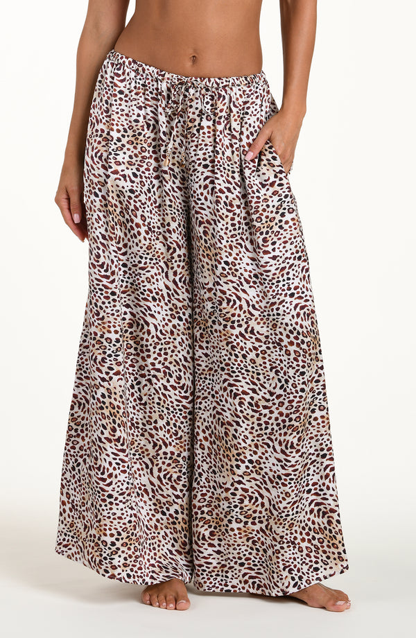 Front image of model wearing leopard printed beach pants with an elastic waist and pockets. 
