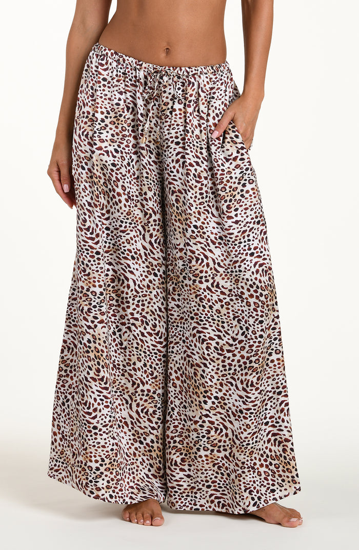 Front image of model wearing leopard printed beach pants with an elastic waist and pockets. 
