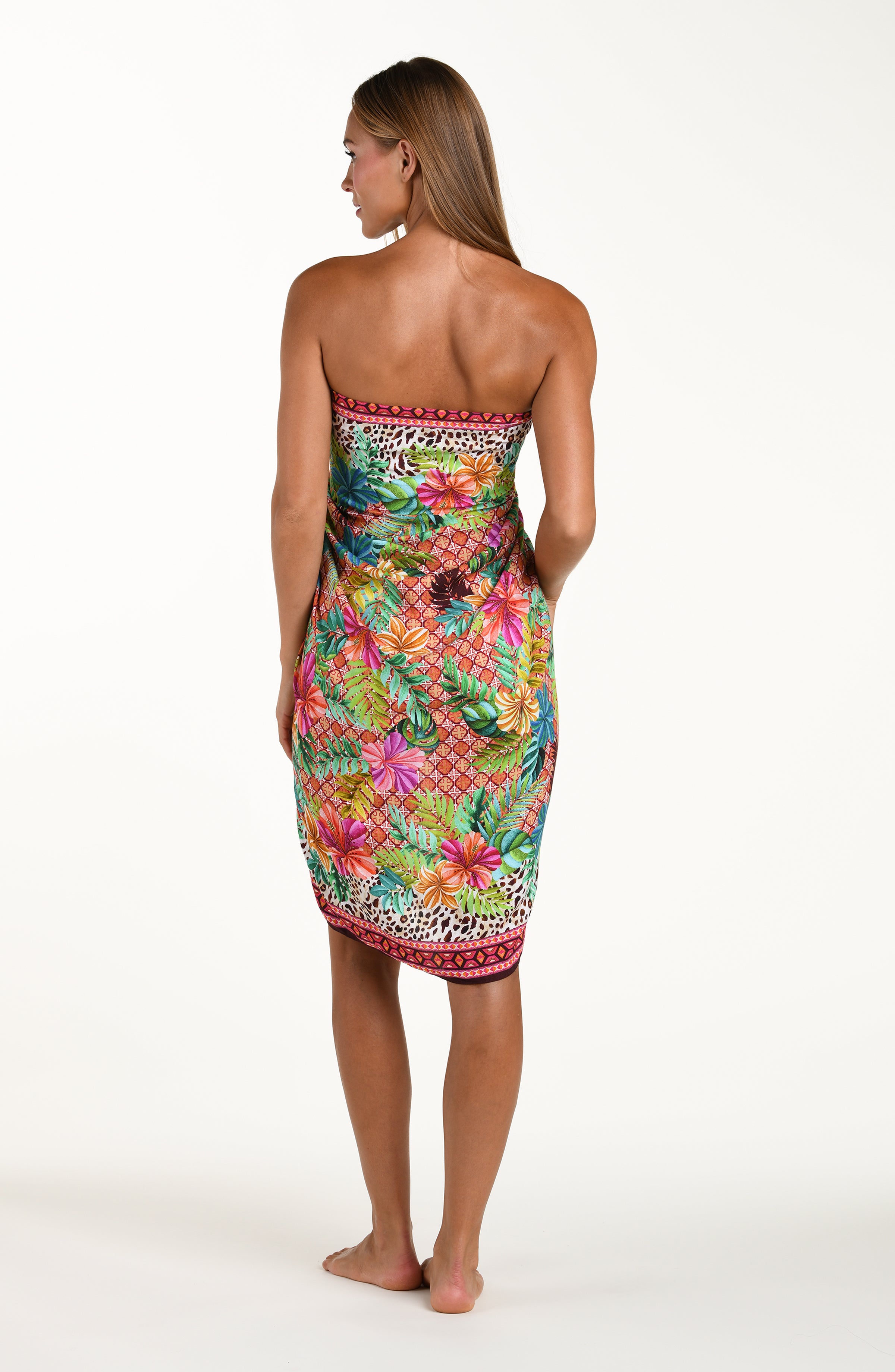 Full body back image of model wearing a multicolored tropical and leopard printed pareo wrap featuring a tie side. This is paired with a matching bikini top.