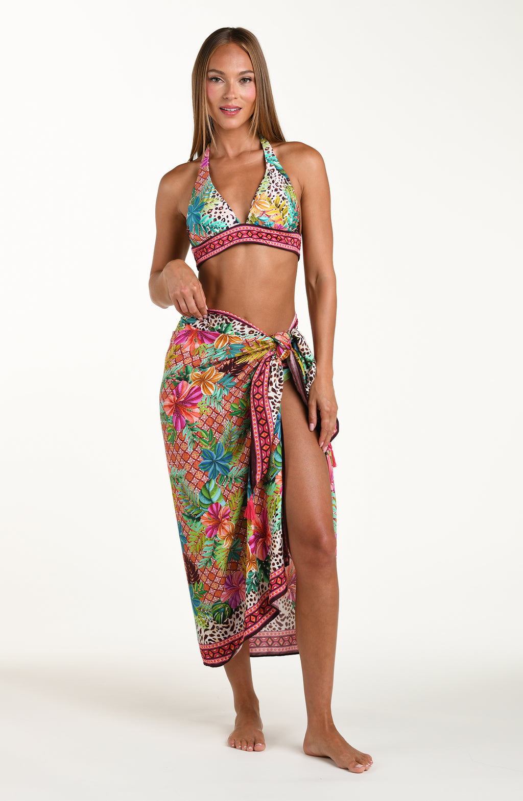 Full body front image of model wearing a multicolored tropical and leopard printed pareo wrap featuring a tie side. This is paired with a matching bikini top. 