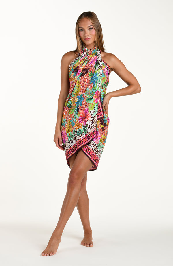 Full body front image of model wearing a multicolored tropical and leopard printed pareo wrap featuring a tie side. Model is showcasing the pareo wrapped at the neck. 