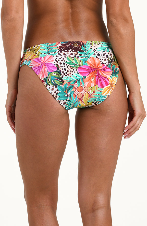 Back image of model wearing a multicolored tropical printed bikini bottom featuring a hipster fit, ruched sides, and moderate rear coverage.