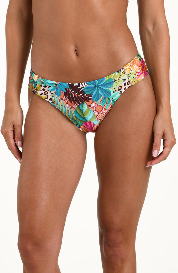Front image of model wearing a multicolored tropical printed bikini bottom featuring a hipster fit, ruched sides, and moderate rear coverage.