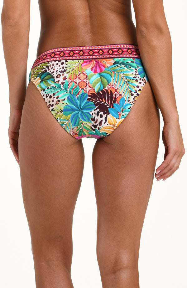 Back image of model wearing a multicolored printed reversible bikini bottom featuring leopard on one side and a tropical print on the other. It has an allover band and moderate rear coverage. 