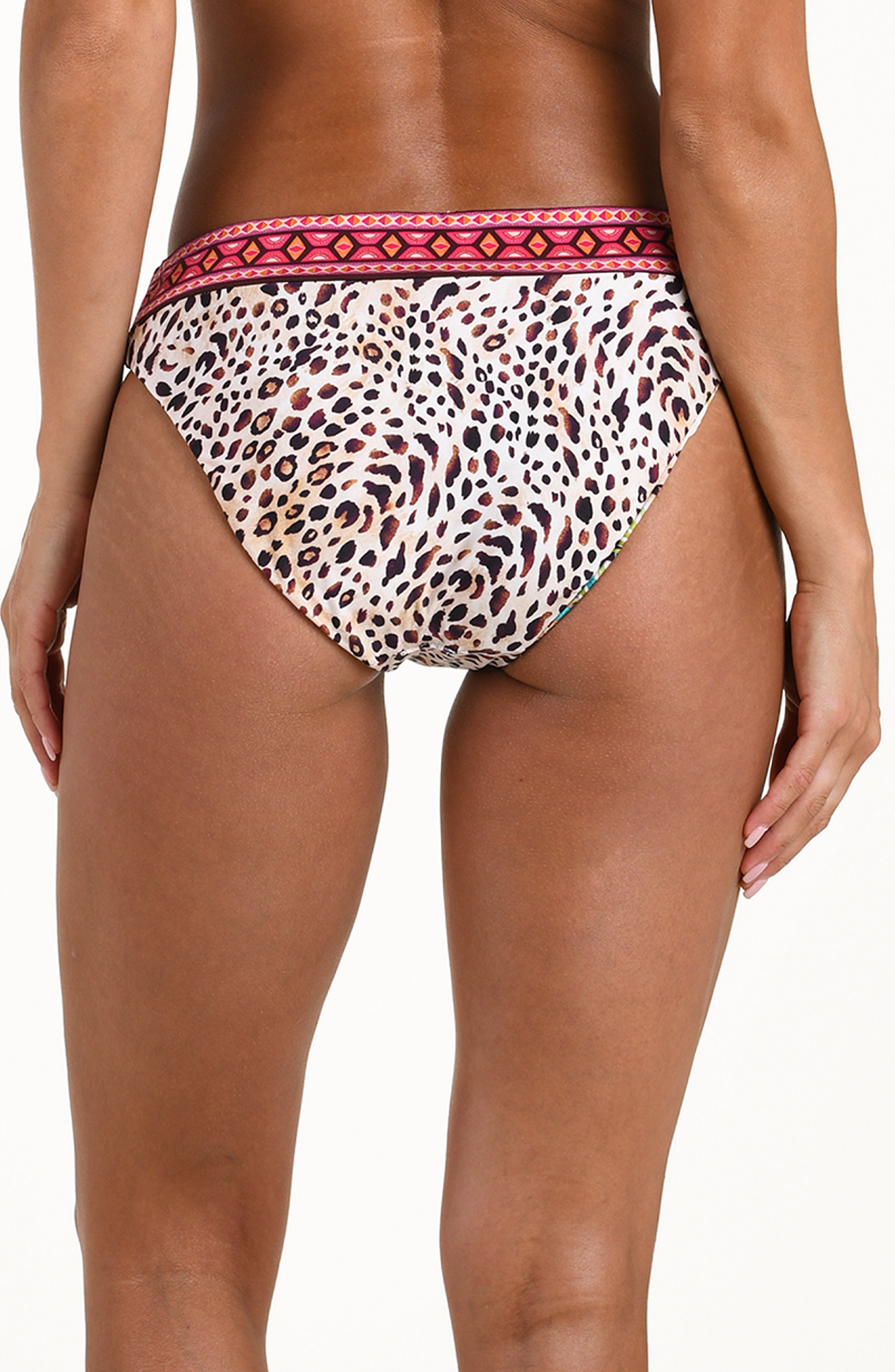 Back image of model wearing a multicolored printed reversible bikini bottom featuring leopard on one side and a tropical print on the other. It has an allover band and moderate rear coverage. 