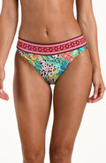 Front image of model wearing a multicolored printed reversible bikini bottom featuring leopard on one side and a tropical print on the other. It has an allover band and moderate rear coverage. 
