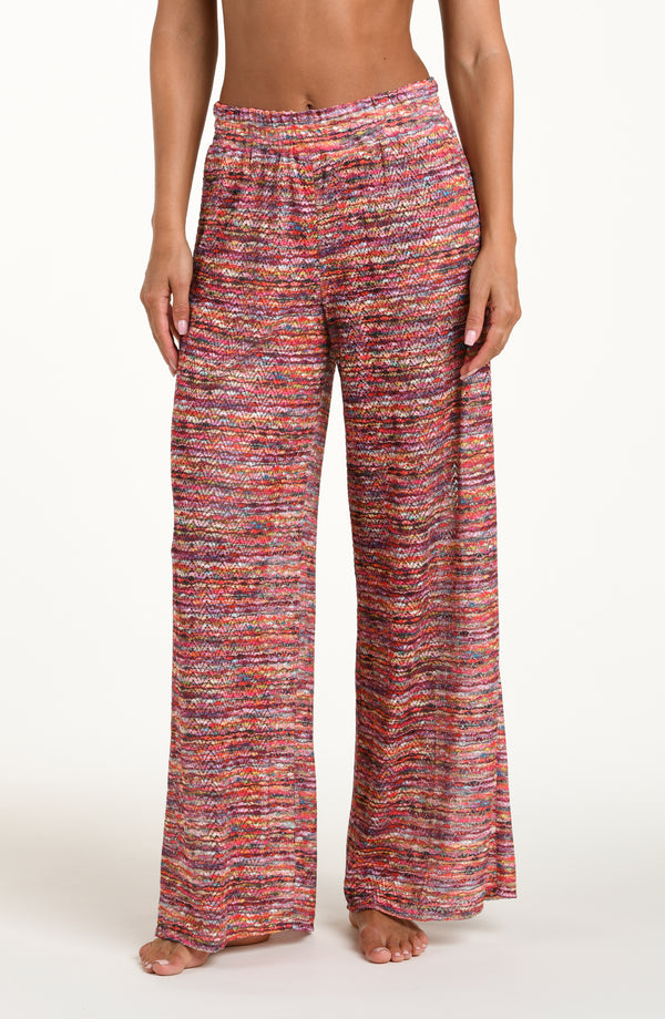 Front image of model wearing long beach pants in a multicolored ripple pattern featuring an elastic waist. 